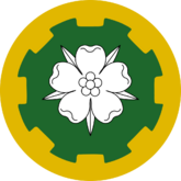 Vert, a rose argent barbed and seeded proper within a border embattled Or